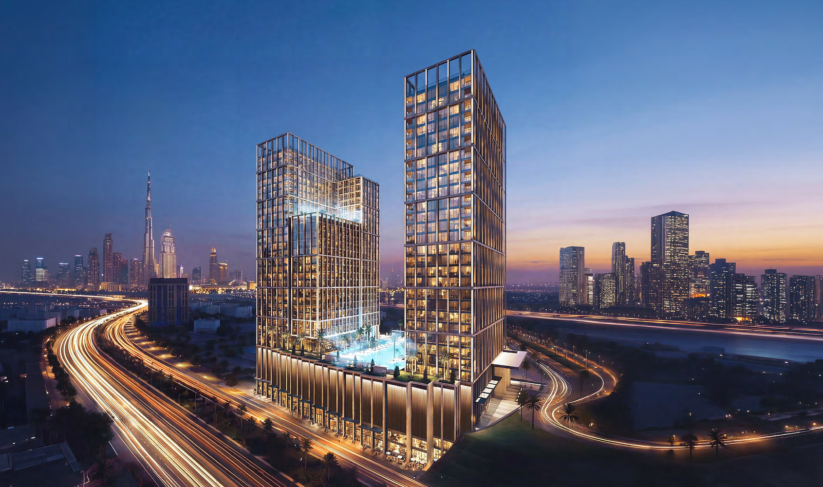 Binghatti Spectre at dusk: two lit towers over the Al Khail Road interchange, Downtown on the horizon.