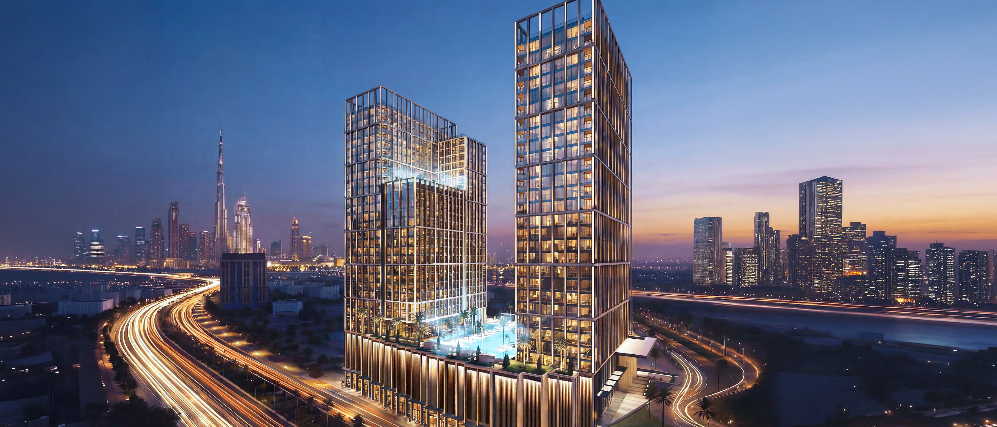 Binghatti Spectre at dusk: two lit towers over the Al Khail Road interchange, Downtown on the horizon.